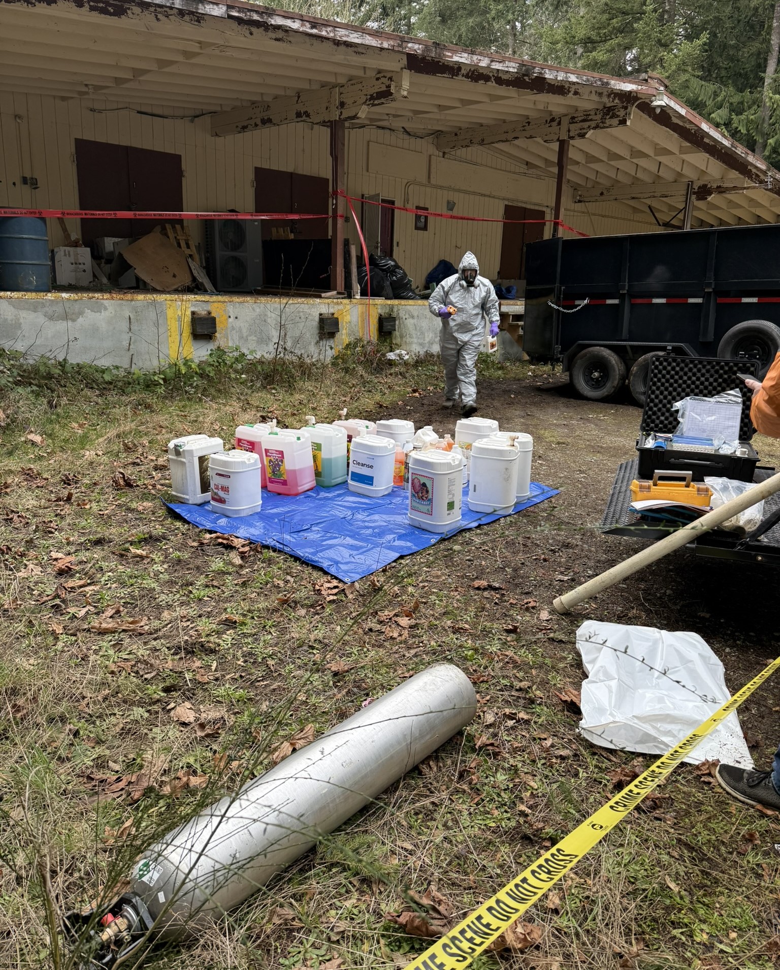 An Ecology spills responder in protective gear inventories containers at a collection site during cleanup operations.